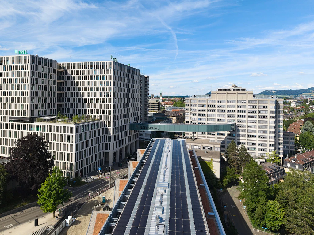 Vue aérienne du campus Insel à Berne avec la maison Marie-Colinet rénovée sur le toit de laquelle l’installation photovoltaïque achevée fournit de l’électricité renouvelable.