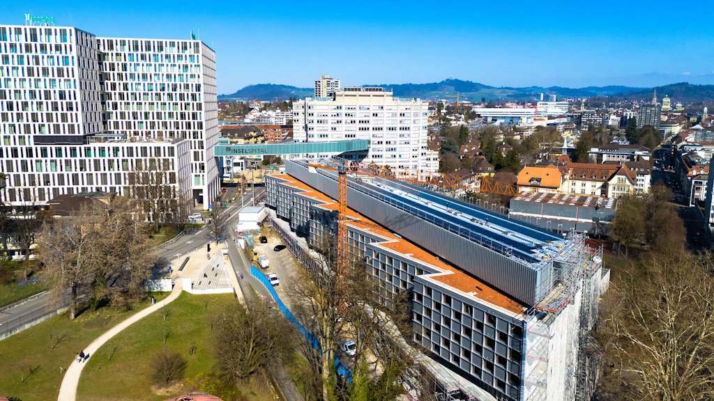 Vue aérienne de la maison Marie-Colinet de l’Inselspital à Berne montrant le chantier et la nouvelle installation photovoltaïque sur le toit.