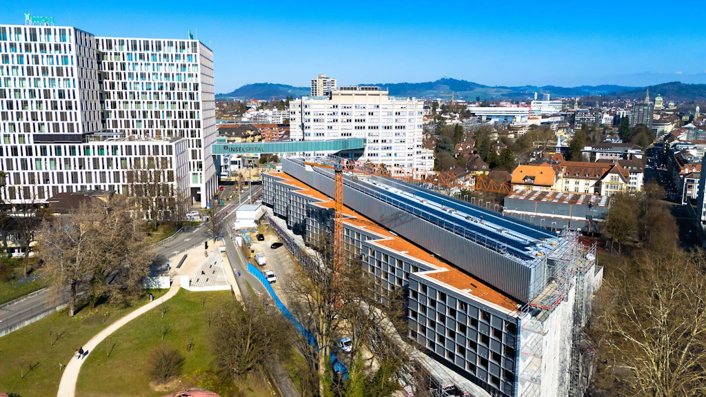 Vue aérienne de la maison Marie-Colinet de l’Inselspital à Berne montrant le chantier et la nouvelle installation photovoltaïque sur le toit.