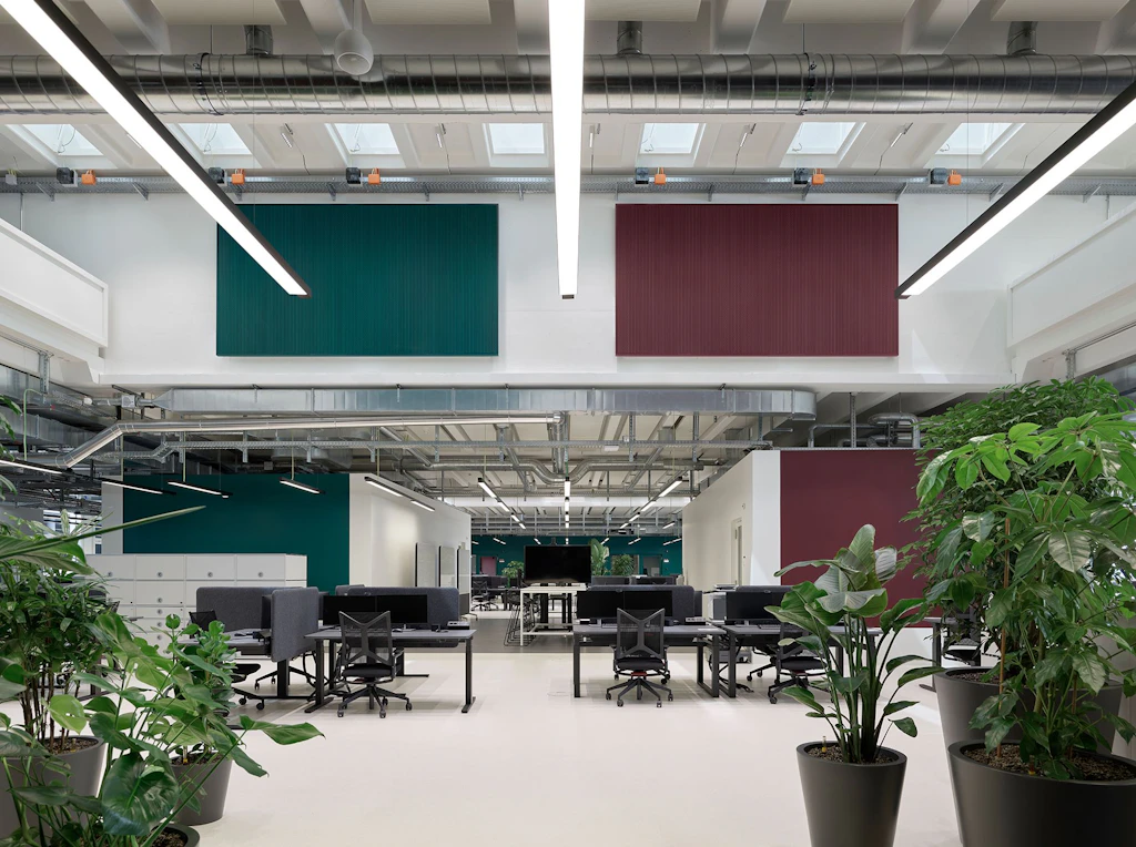 Intérieur du studio radio SRF rénové à Leutschenbach: grand espace ouvert avec postes de travail et installations techniques visibles au plafond.